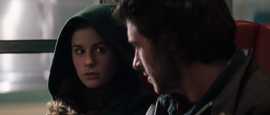 Rogue and Logan are sitting in a train. Rogue looks to Logan as she listens to his words of wisdom.